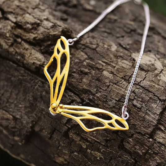 Hollow Butterfly Wings Necklace LFJF0063B gold color from back on piece of wood- Tan Tan Gallery