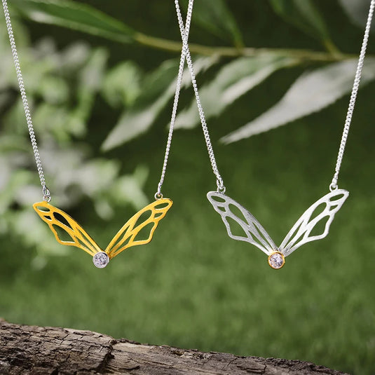 Hollow Butterfly Wings Necklace LFJF0063B silver and gold color with a blurry background- Tan Tan Gallery